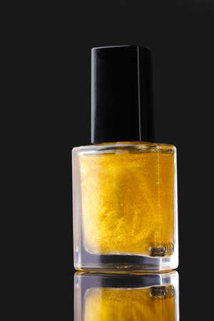 Golden nail polish on black backgroundの写真素材