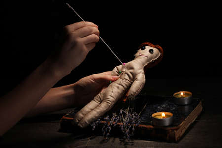 Voodoo doll girl pierced by a needle on a wooden table in the candlelightの写真素材