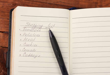 Shoping list and pen on wooden tableの写真素材