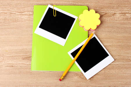 Photo papers and green notebook on wooden backgroundの写真素材