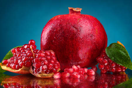 ripe pomegranate fruit with leaves on blue backgroundの写真素材