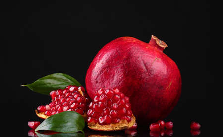 ripe pomegranate fruit with leaves on black backgroundの写真素材