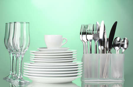 Clean plates, glasses, cup and cutlery on green backgroundの写真素材