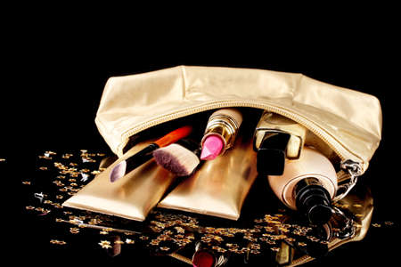 Beautiful golden makeup bag and cosmetics isolated on blackの写真素材