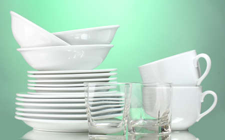 Clean plates, cup and glasses on green backgroundの写真素材