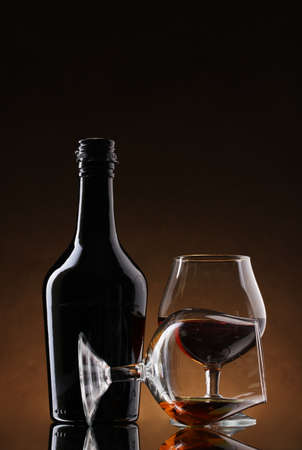 Glasses of brandy and bottle on brown backgroundの写真素材