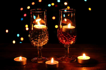 Amazing composition of candles and glasses on wooden table on bright backgroundの写真素材