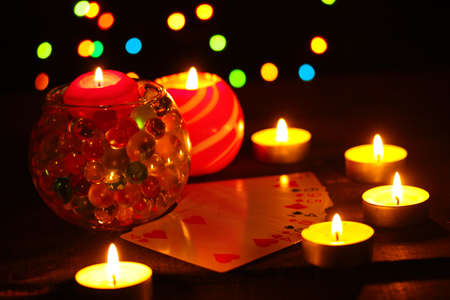 Candles and playing cards on wooden table on bright backgroundの写真素材