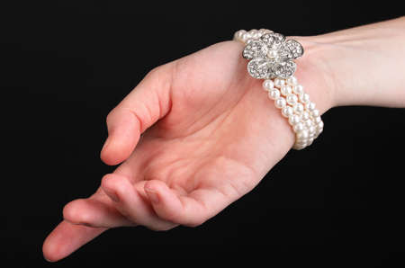 Pearl bracelet on hand isolated on blackの写真素材