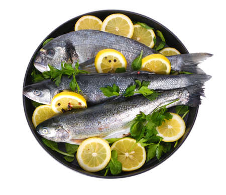 Fresh fishes with lemon, parsley and pepper on plate isolated on whiteの写真素材