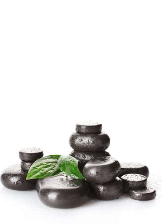 Spa stones with drops and green leaves isolated on whiteの写真素材