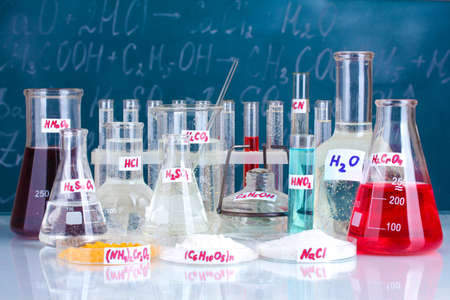 Test-tubes with various acids and other chemicals on the background of the blackboardの写真素材