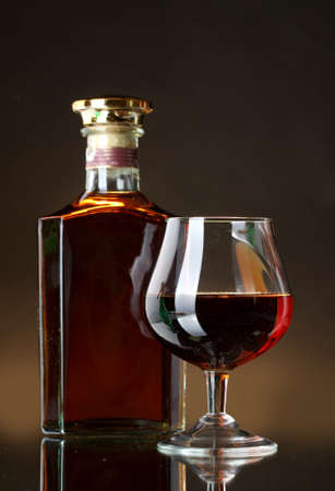 Glass of brandy and bottle on brown backgroundの写真素材