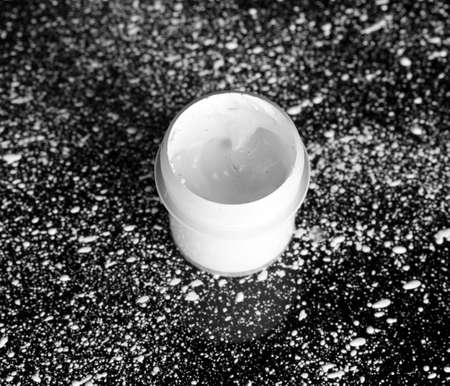 Jar with white gouache on black background, spattered with white paint close-upの写真素材