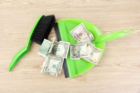 Sweeps money in the shovel on wooden background close-upの写真素材