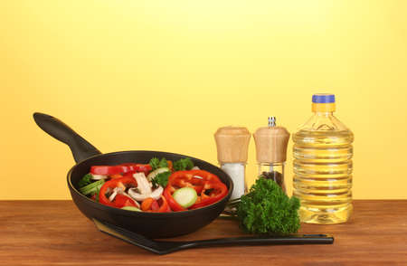 frying pan with vegetables on yellow backgroundの写真素材
