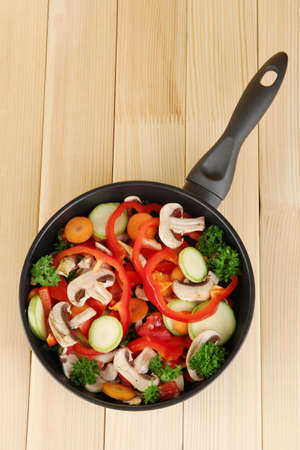 frying pan with vegetables on wooden backgroundの写真素材