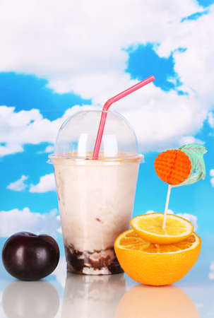Delicious milk shake with fruit on table on sky backgroundの写真素材