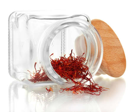 Stigmas of the saffron poured out a glass jar isolated on whiteの写真素材