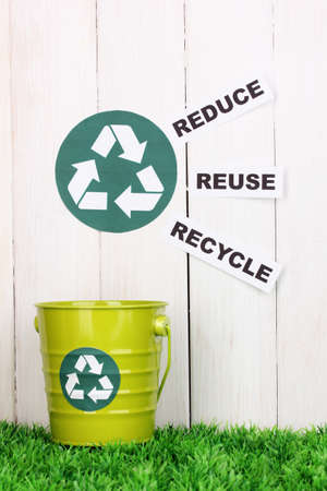 Recycling bin on green grass near wooden fenceの写真素材