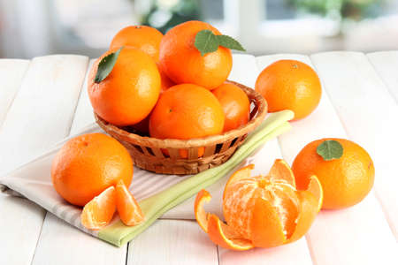 tangerines with leaves in a beautiful basket, on white wooden tableの写真素材