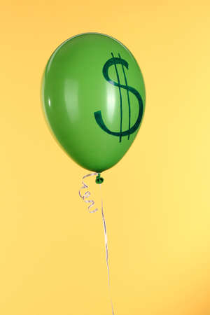 Hand holds green one balloon with showing dollar on yellow backgroundの写真素材