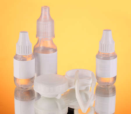 Eye drops and lenses on orange backgroundの写真素材
