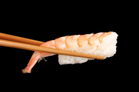holding sushi with chopsticks isolated on blackの写真素材