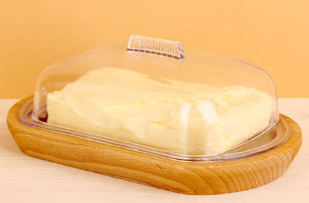 Butter on wooden holder on wooden table on beige backgroundの写真素材