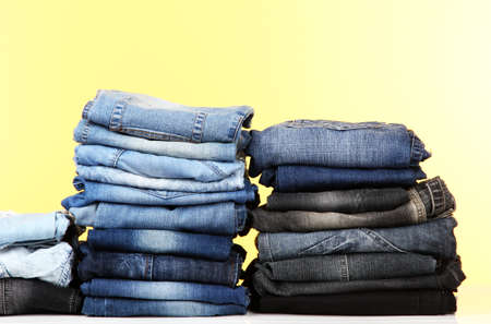 Many jeans stacked in a piles on yellow backgroundの写真素材