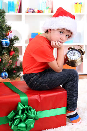 Little boy with big gift and clock in anticipation of New Yearの写真素材