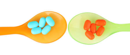 Plastic spoons with color pills, isolated on whiteの写真素材