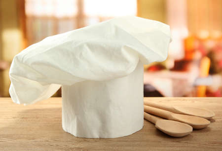 Chef's hat with spoons on table in kitchenの写真素材