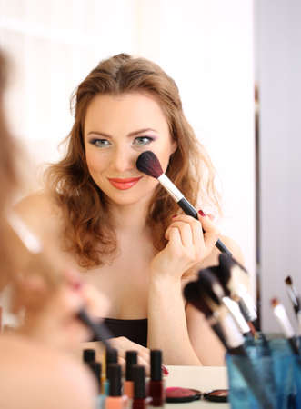 Young beautiful woman making make-up near mirrorの写真素材