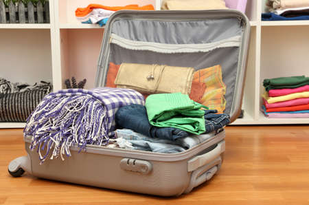 Open grey suitcase with clothing in roomの写真素材