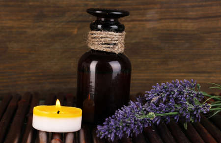 Bottle with aromatic oils with accessories for relaxation on wooden table on wooden backgroundの写真素材
