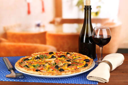 Tasty pizza with wine on wooden table on room background close-upの写真素材