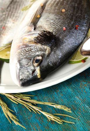 Two fish dorado with lemon on plate on blue wooden table close-upの写真素材