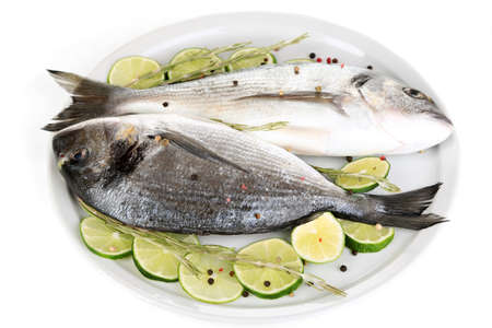 Two fish dorado with lemon on plate isolated on whiteの写真素材
