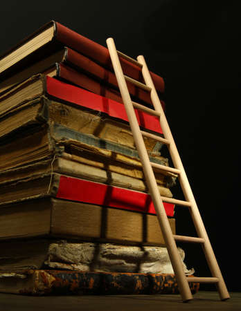 Old books and wooden ladder, on black backgroundの写真素材