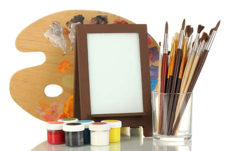 Photo frame as easel with artist's tools isolated on whiteの写真素材