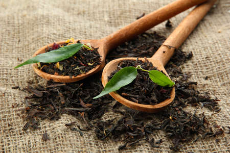 Dry tea with green leaves in wooden spoons, on burlap backgroundの写真素材