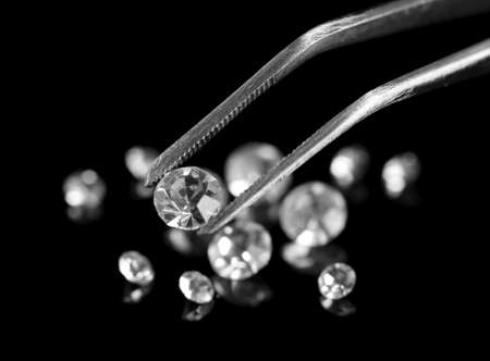 Beautiful shining crystal (diamond) in the tweezers, on black backgroundの写真素材