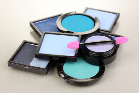 Bright eye shadows and sponge brushes for foundation on grey backgroundの写真素材