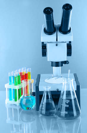 Test tubes with colorful liquids and microscope in blue lightの写真素材