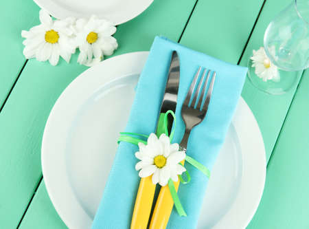 Knife and fork wrapped in napkin, on plate, on color wooden backgroundの写真素材