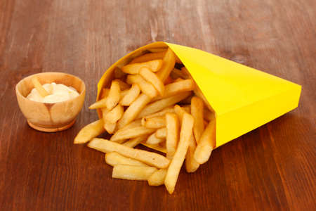 French fries in paper bag on wooden table close-upの写真素材