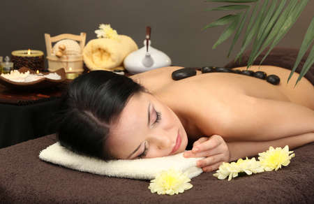 Beautiful young woman in spa salon with spa stones, on dark backgroundの写真素材