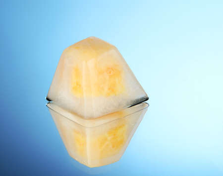 Ice cube with orange piece piece, on blue backgroundの写真素材