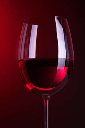 Glass of wine on bright red backgroundの写真素材